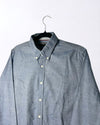 Blue button-up shirt on a hanger against a white background